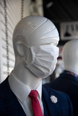 Los Angeles, CA / USA - 19 Mayıs 2020: COVID-19 karantina kısıtlamaları kaldırılırken, bir moda bölgesi tüccarı yüz maskesi takan bir mağaza mankenini giydiriyor