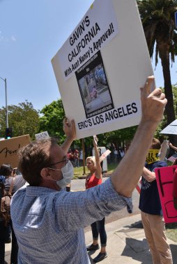 Los Angeles, CA / USA - 8 Mayıs 2020: Anti-Covid-19 karantina protestocusu sokaklardaki evsizlerin görmezden gelinen sağlık sorununa işaret ediyor