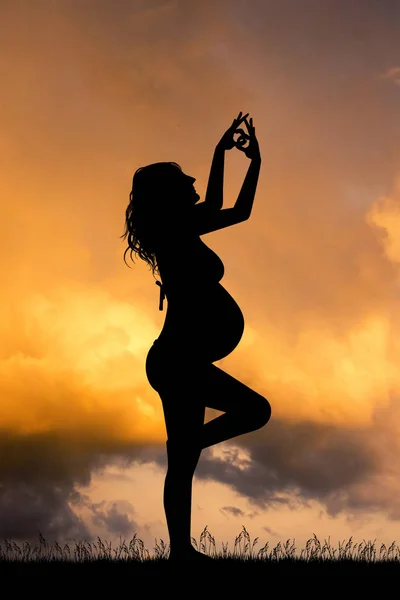 Una ragazza incinta che fa yoga al tramonto — Foto Stock