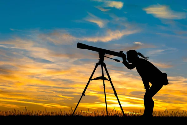 Flicka och teleskop vid solnedgången — Stockfoto
