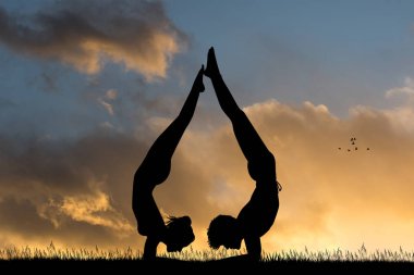 Kız ve erkek gün batımında yoga yapıyor.