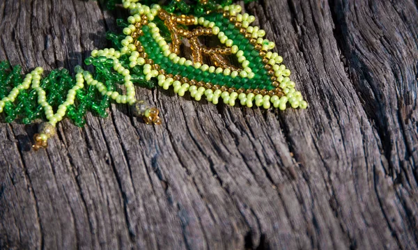 green bead-work lace on a wooden background