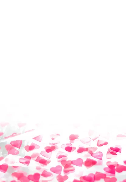 Roze hartvormige confetti op witte achtergrond. Abstracte liefde, Valentijnsdag achtergrond. Kopieer ruimte, zachte focus. — Stockfoto