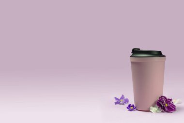 Pembe arka planda termo bardak ve menekşe çiçekleri. Camlar yeniden kullanılıyor.