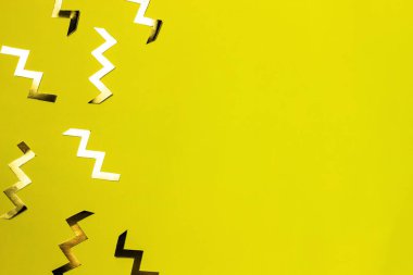 Sarı arka planda altın zig zag şeklinde konfeti. Kutlama arkaplanı ya da afiş. Üst görünüm, düz görünüm, kopyalama alanı.