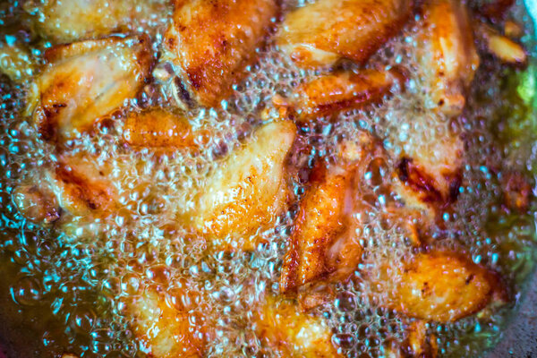 Close up fried chicken wings in boiling oil.