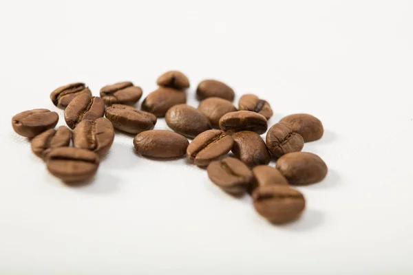 Макроизображение темно-ароматных кофейных зерен на белом фоне — стоковое фото