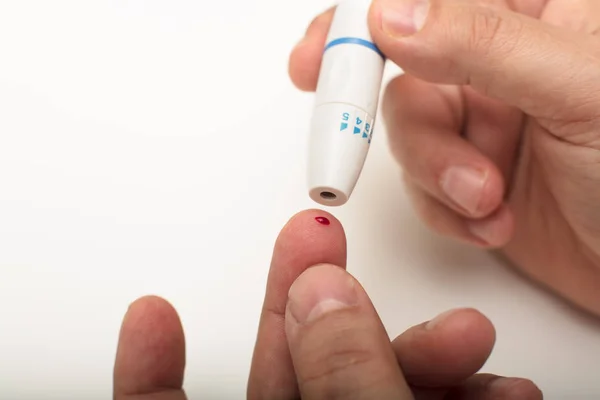 Man pricking his finger with a lancet — Stock Photo, Image