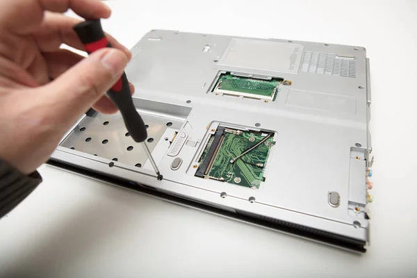 Hombre haciendo ajustes y reparaciones a un ordenador portátil — Foto de Stock