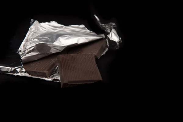 Chocolate envuelto en papel de aluminio sobre tela oscura —  Fotos de Stock