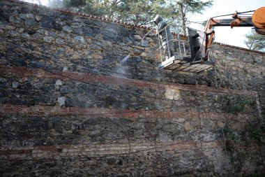 Eski taş ve tuğla duvar gri yağmur takım elbiseli adam temizler
