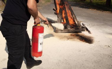 Genç adam bir toz işaret yazın yangın söndürücü ileriye doğru ateş ciddi bir durumda
