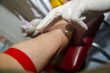 Doktor muayenehanesindeki hastadan kan örneği alan hemşire. 