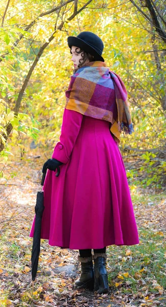 Niña en un abrigo carmesí brillante caminando en el bosque soleado día de otoño —  Fotos de Stock