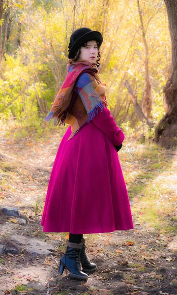Menina em um casaco carmesim brilhante andando na floresta ensolarado dia de outono — Fotografia de Stock