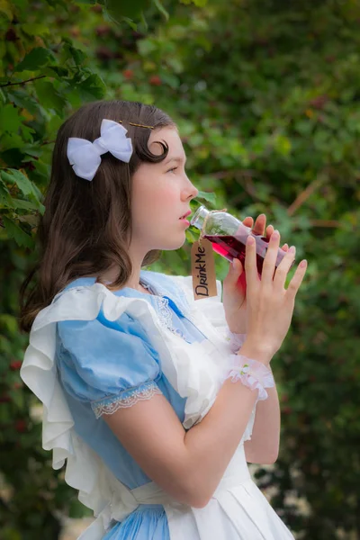 Meisje in beeld van sprookje heldin dranken drinken van glazen fles — Stockfoto