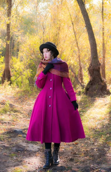 Menina em um casaco carmesim brilhante andando na floresta ensolarado dia de outono — Fotografia de Stock