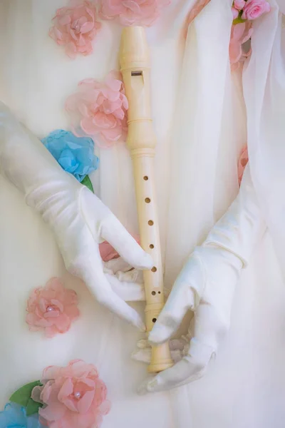 Flute in female hands in white gloves close-up