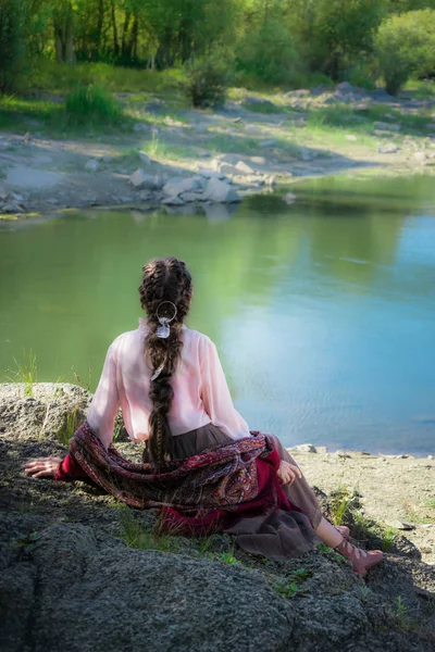 Bella donna boho, seduta su una roccia sulla riva del fiume . — Foto Stock