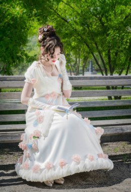 genç kadın bir bankta oturan bir kitap okuyor.