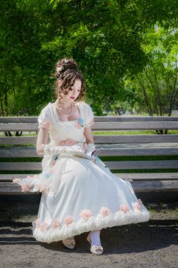 genç kız bir bankta oturan bir kitap okuyor.