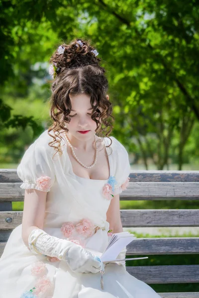 Mujer joven está leyendo un libro sentado en un banco . — Foto de Stock