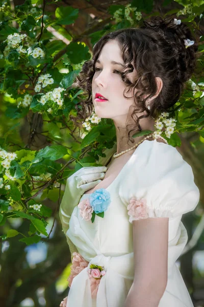 Mujer joven en un vestido largo de novia blanca en el árbol de flores —  Fotos de Stock