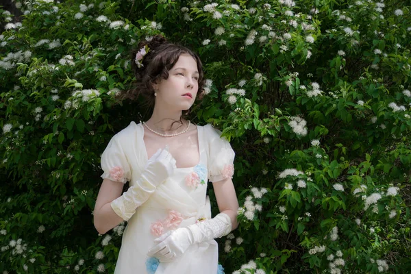 Jovem mulher em um vestido longo elegante branco em flores — Fotografia de Stock