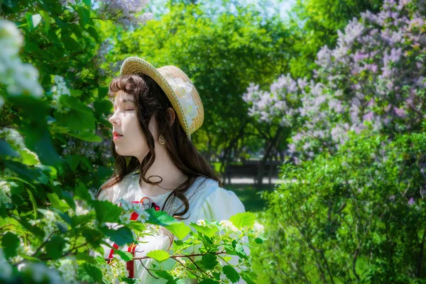 Ragazza in abito bianco e cappello di paglia vicino ai fiori biancospino — Foto Stock