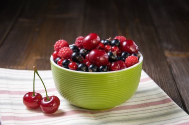 Ahşap arka plan üzerinde yeşil bir tabak içinde çilek