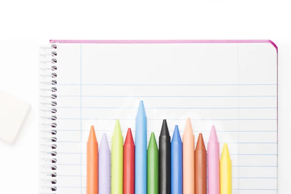 Pohled shora na barevné pastelky na notebooku a bílé pozadí — Stock fotografie