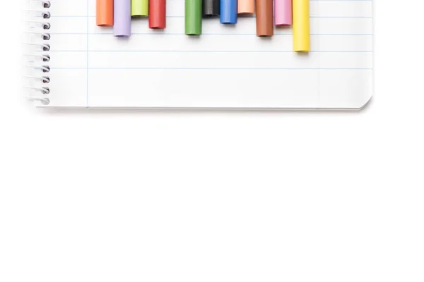 Pastelli colorati su notebook e sfondo bianco vista dall'alto — Foto Stock