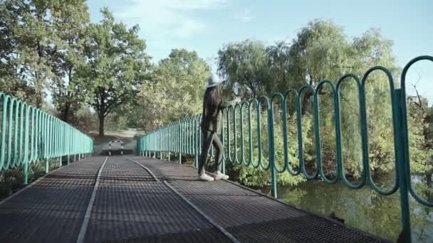Приваблива Молода Жінка Капелюсі Йде Мосту Над Озером Осінньому Парку — стокове відео