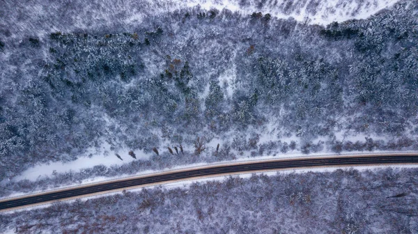 Загородная дорога, проходящая по красивым заснеженным пейзажам. Вид с воздуха. Фотография дронов — стоковое фото