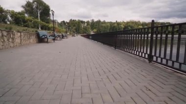 Şehir parkındaki boş bir göl kordonunun önünde kamera hareketi. Bulutlu sonbahar günü.