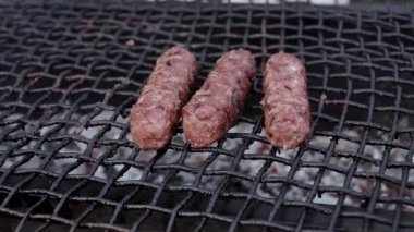 Adam ızgarada taze etle sosis pişiriyor. Mangal mangalı ya da kebap ateşte pişmiş. Izgarayı yakar ve takla atar. Yaz yemek servisi.