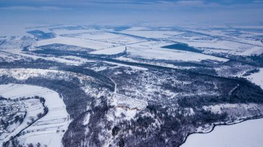 Kışın aşağı doğru orman manzarası. Ormandaki kış manzarası. Kış köknar ormanının üzerinde uçuyorlar. Yüksek karlı ağaçların yukarıdan görünüşü. Karda ağaçlar.