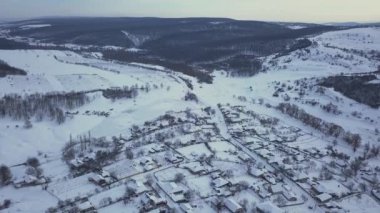 Kışın tarlalar ve ormanlar arasındaki hava manzaralı köy. Kış manzarası karla kaplı tarlalar ve kırsal kesimlerdeki ağaçlar.