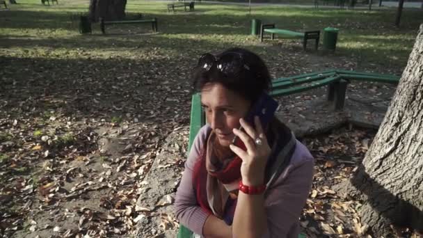 Sorrindo Morena Mulher Falando Por Smartphone Enquanto Sentado Banco Parque — Vídeo de Stock