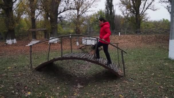 Eine Frau Roter Jacke Geht Auf Einer Holzbrücke Herbstpark — Stockvideo