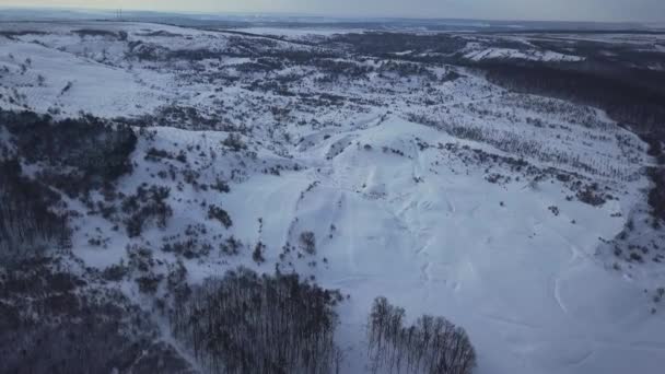 Survoler les collines enneigées et les terres agricoles en hiver à l'aube 