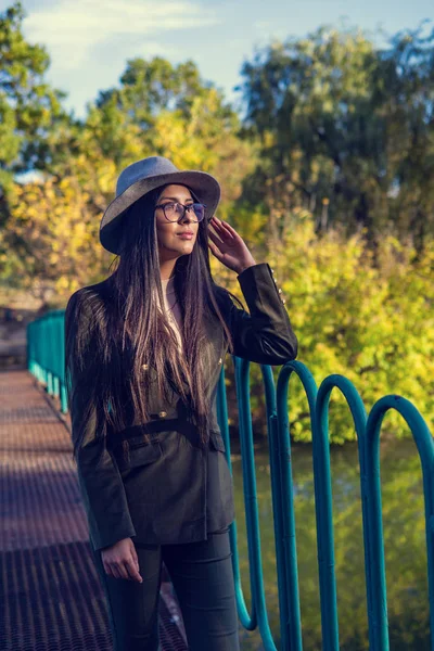 Close up de mulher feliz emocionalmente morena com cabelo longo e chapéu, sorrindo para a câmera. Modelo bonito com maquiagem perfeita após o salão, posando no parque. Conceito de moda e beleza . — Fotografia de Stock