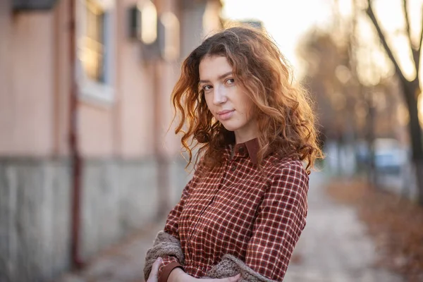 Dreaming young woman with spectacular curly red ginger hair looking at camera posing outdoor in downtown street. Female portrait. — Stock Photo, Image