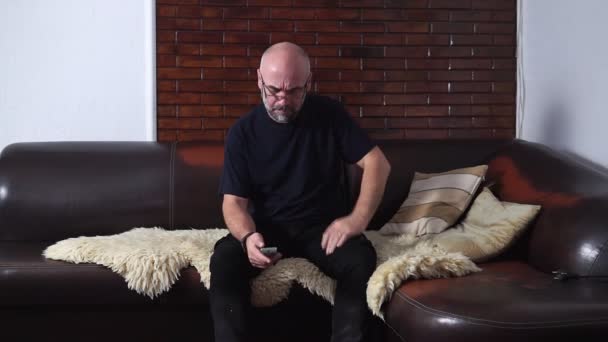 Homem barbudo muda os canais de TV enquanto sentado no sofá — Vídeo de Stock