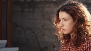 Olağanüstü kıvırcık kızıl saçlı genç bir kadın şehir merkezindeki sokakta kameraya bakıyor. Kadın portresi.