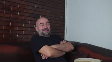 Televizyon izleyen sakallı duygusal adam.