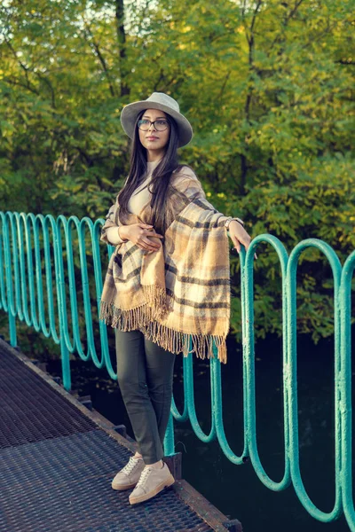 Close up de mulher feliz emocionalmente morena com cabelo longo e chapéu, sorrindo para a câmera. Modelo bonito com maquiagem perfeita após o salão, posando no parque. Conceito de moda e beleza . — Fotografia de Stock