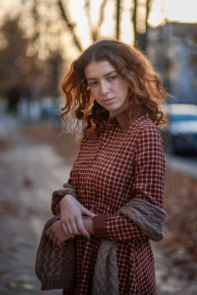 Sonhando jovem mulher com cabelo encaracolado gengibre vermelho espetacular olhando para câmera posando ao ar livre no centro da rua. Retrato feminino . — Fotografia de Stock