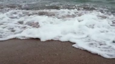 Kumlu sahilde denizin yumuşak dalgası. Yavaş çekim.