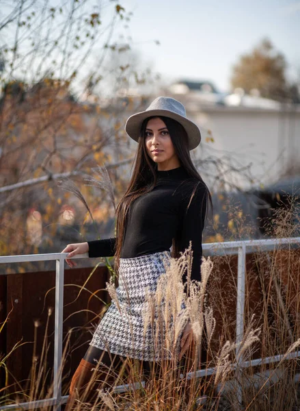 Stylish girl in a hat with long hair posing against the backdrop of the building — Stock Photo, Image